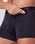 Man placing AirPods into pocket of black boxer briefs with patented pocket