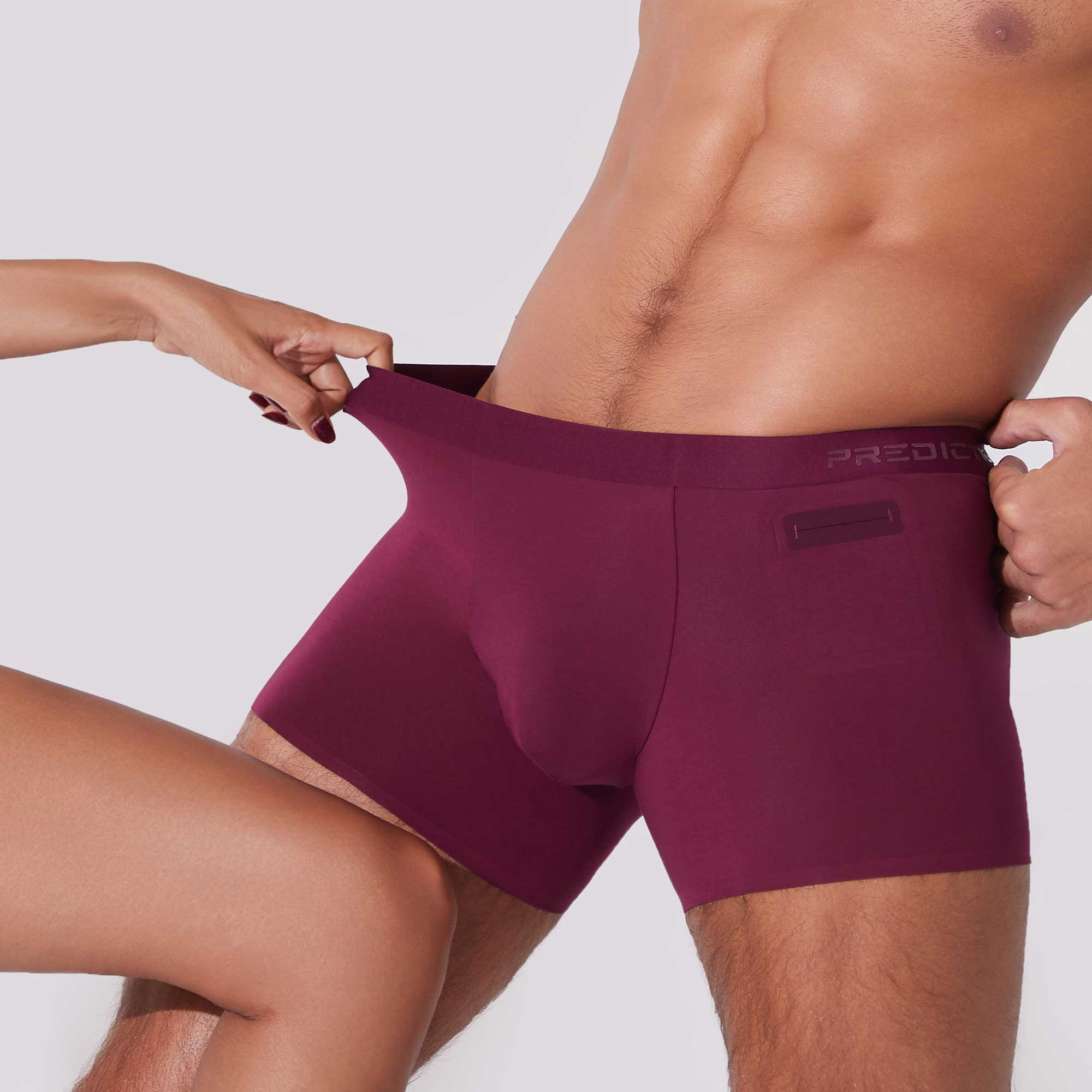 Man stretching burgundy boxer briefs showing flexible 4-way stretch fabric
