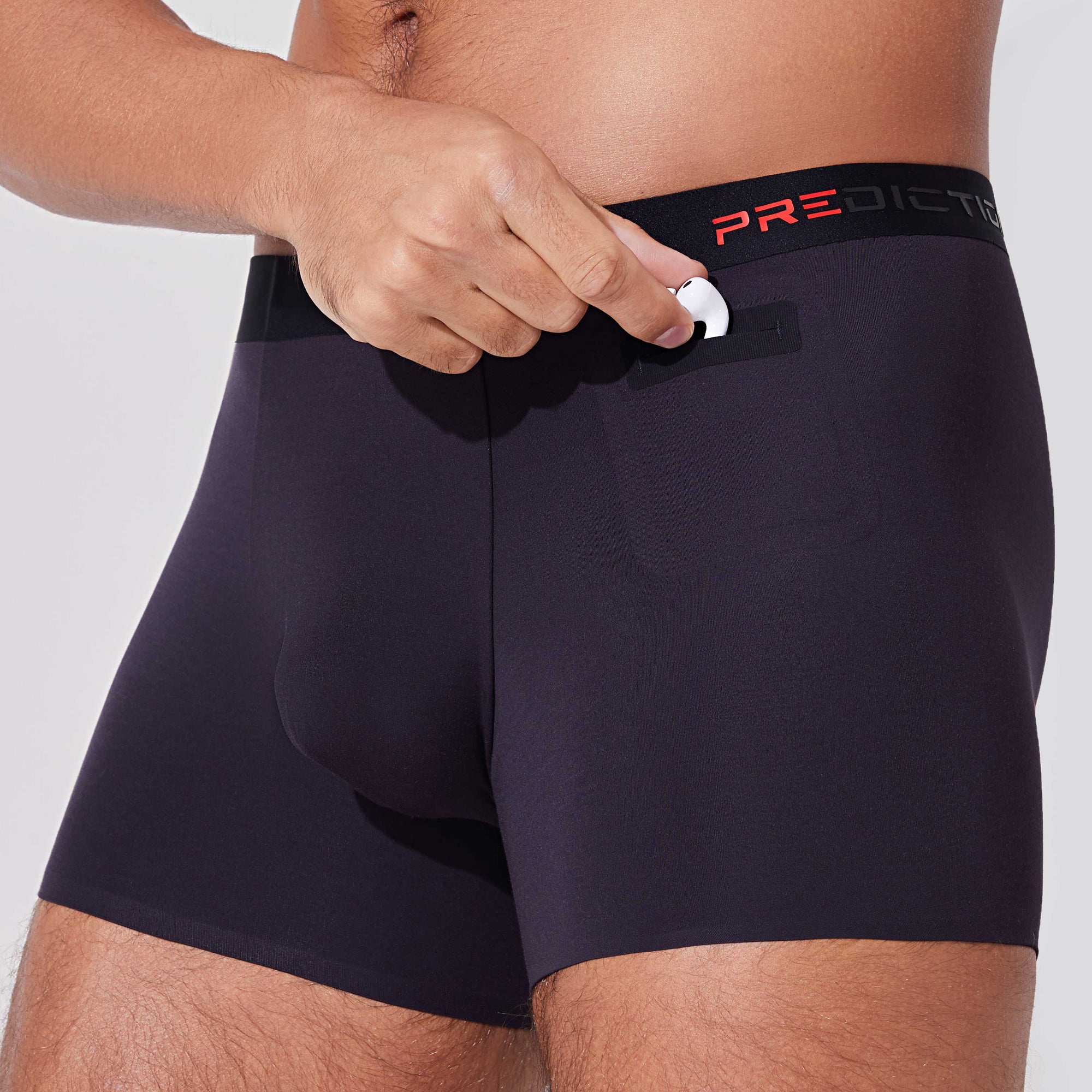 Man placing AirPods into pocket of black boxer briefs with patented pocket