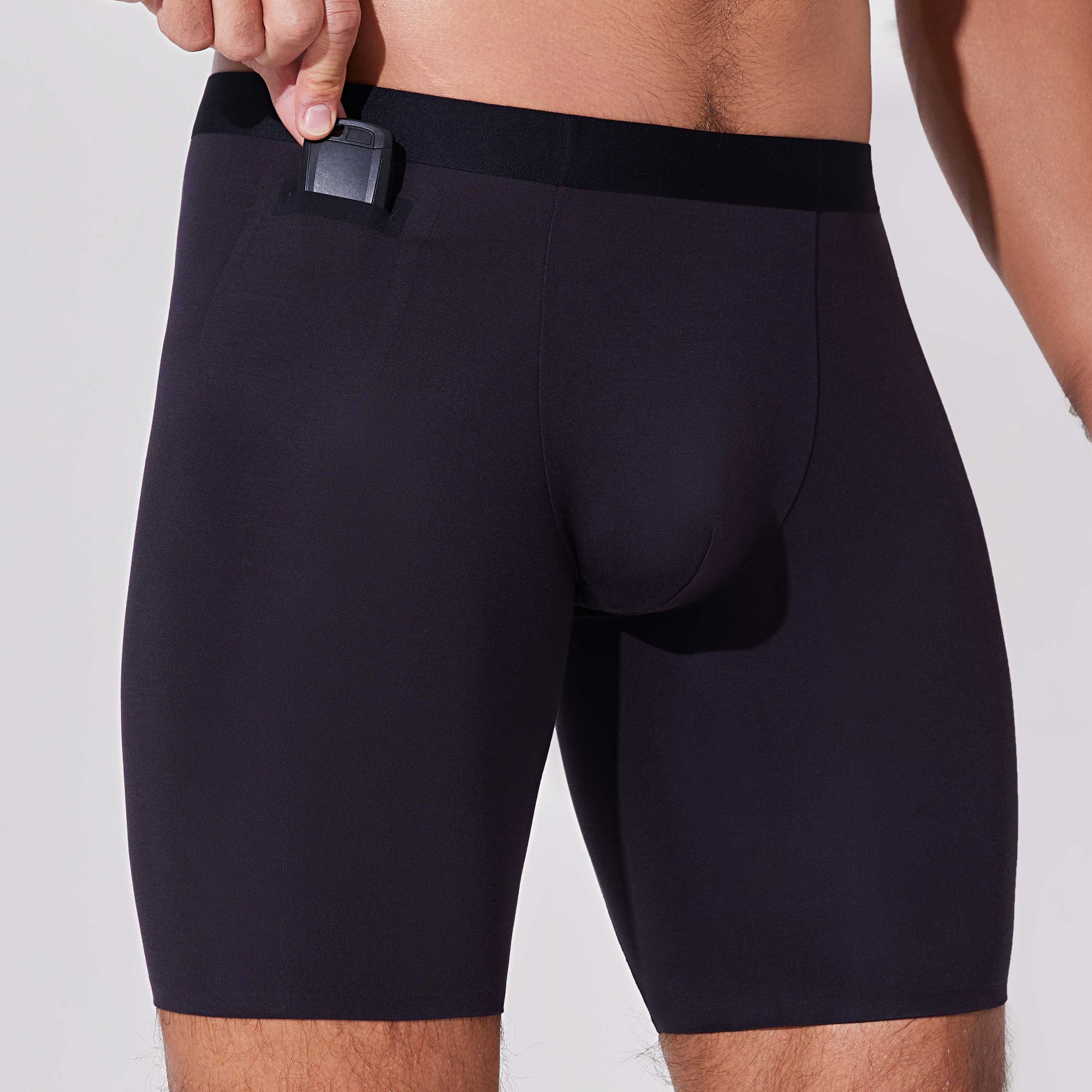 Man placing car key into pocket of black boxer briefs with patented pocket