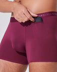 Man placing car key into pocket of burgundy boxer briefs with patented pocket