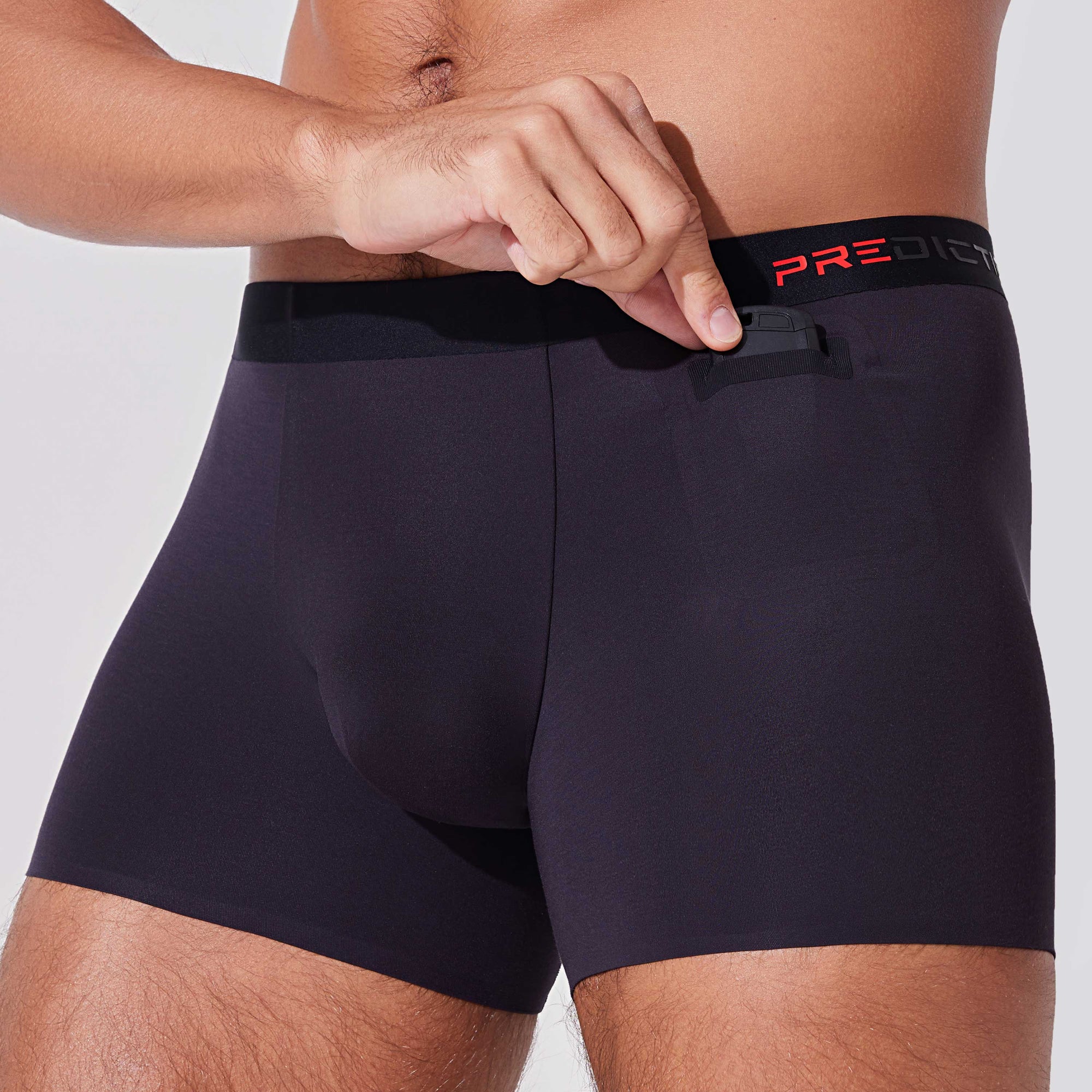 Man placing car remote into pocket of black boxer briefs with patented pocket