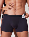 Couple placing a condom into the pocket of black boxer briefs showing functional pocket use